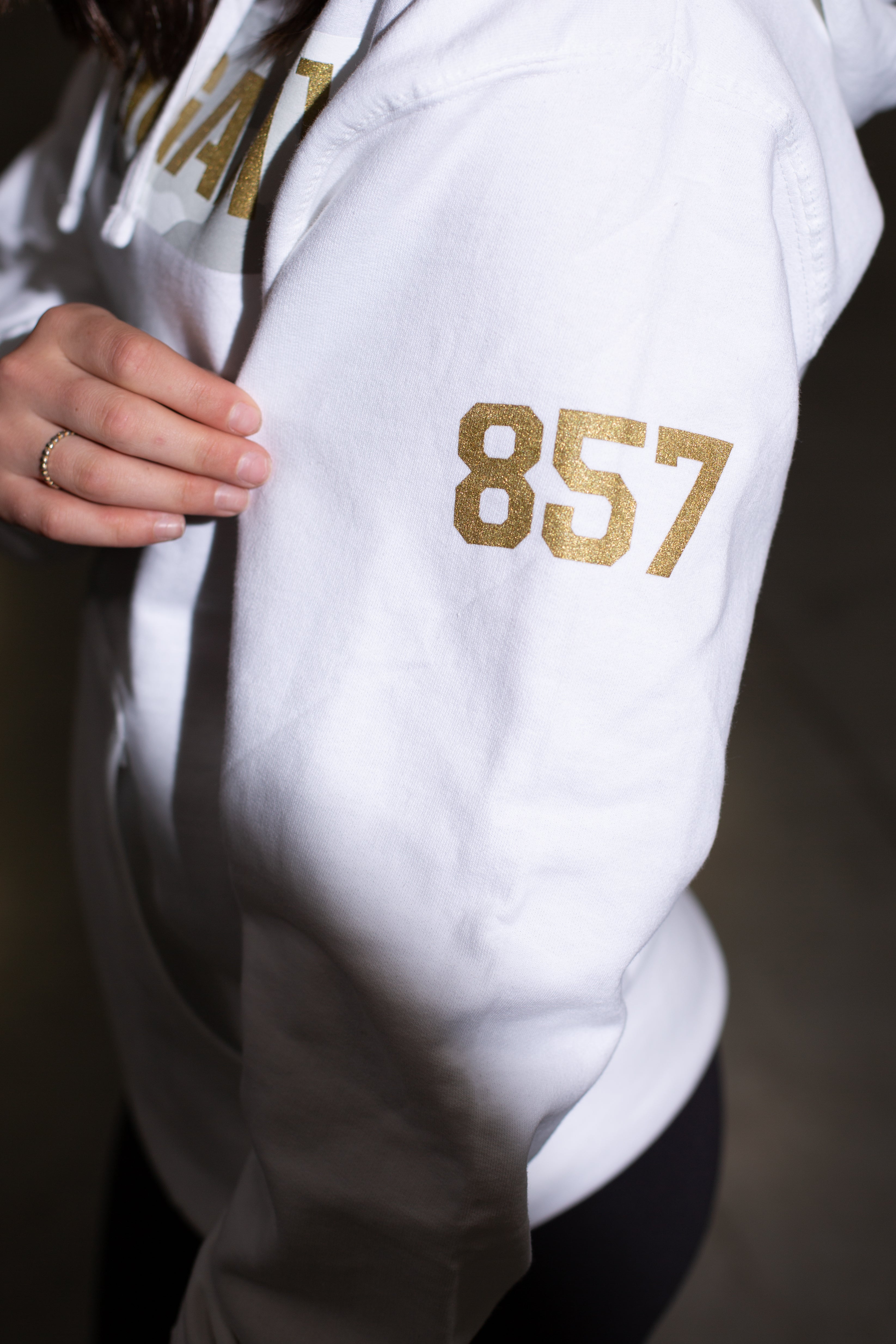 White hoodie with gold "857" print on the sleeve and "Lia Block SNOW CAMO CENSOR BAR" text on the chest.