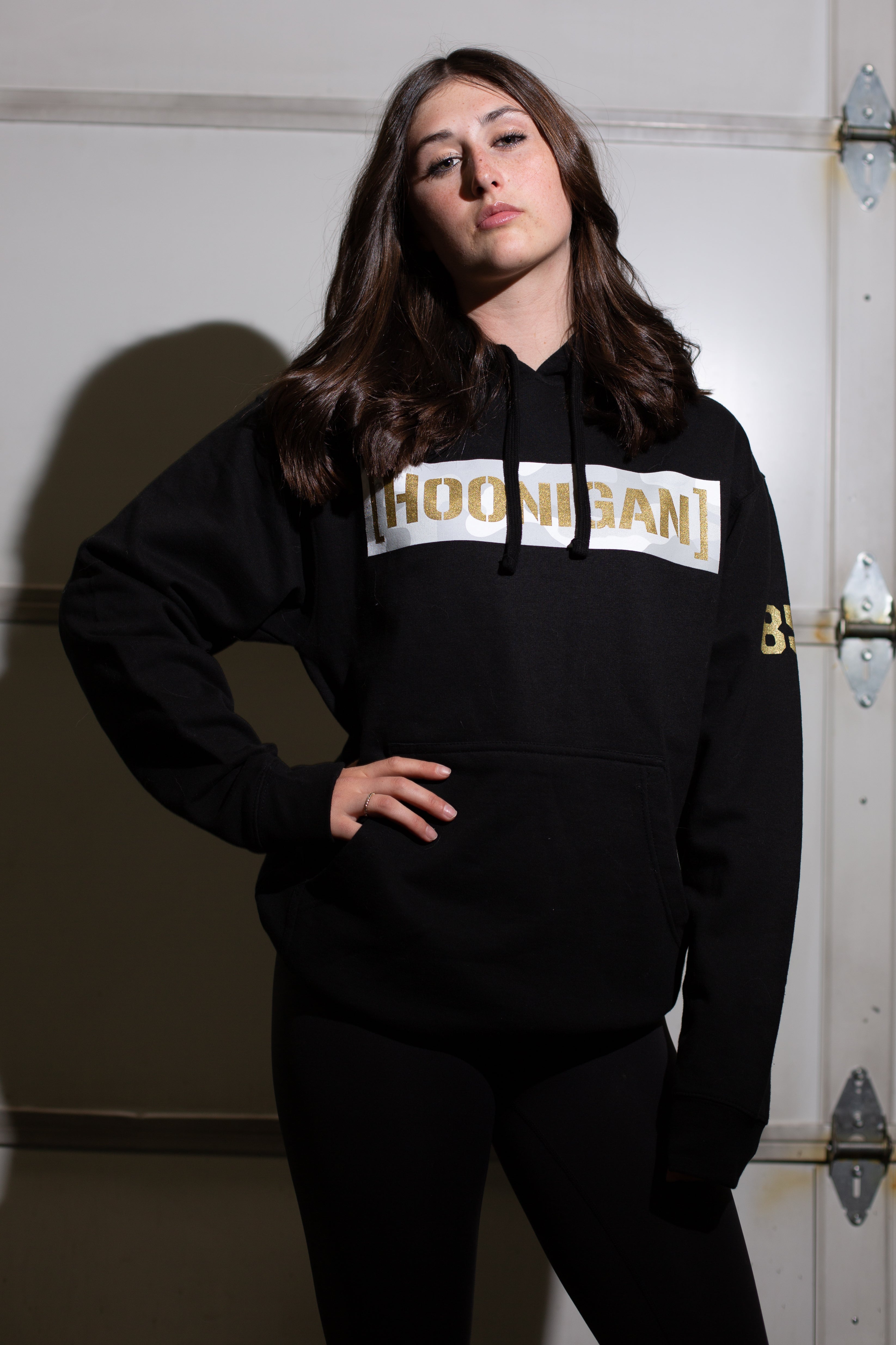 Black hoodie with "HOODIGANT" in gold and white lettering across the chest, featuring a camouflage censor bar and a front pocket.