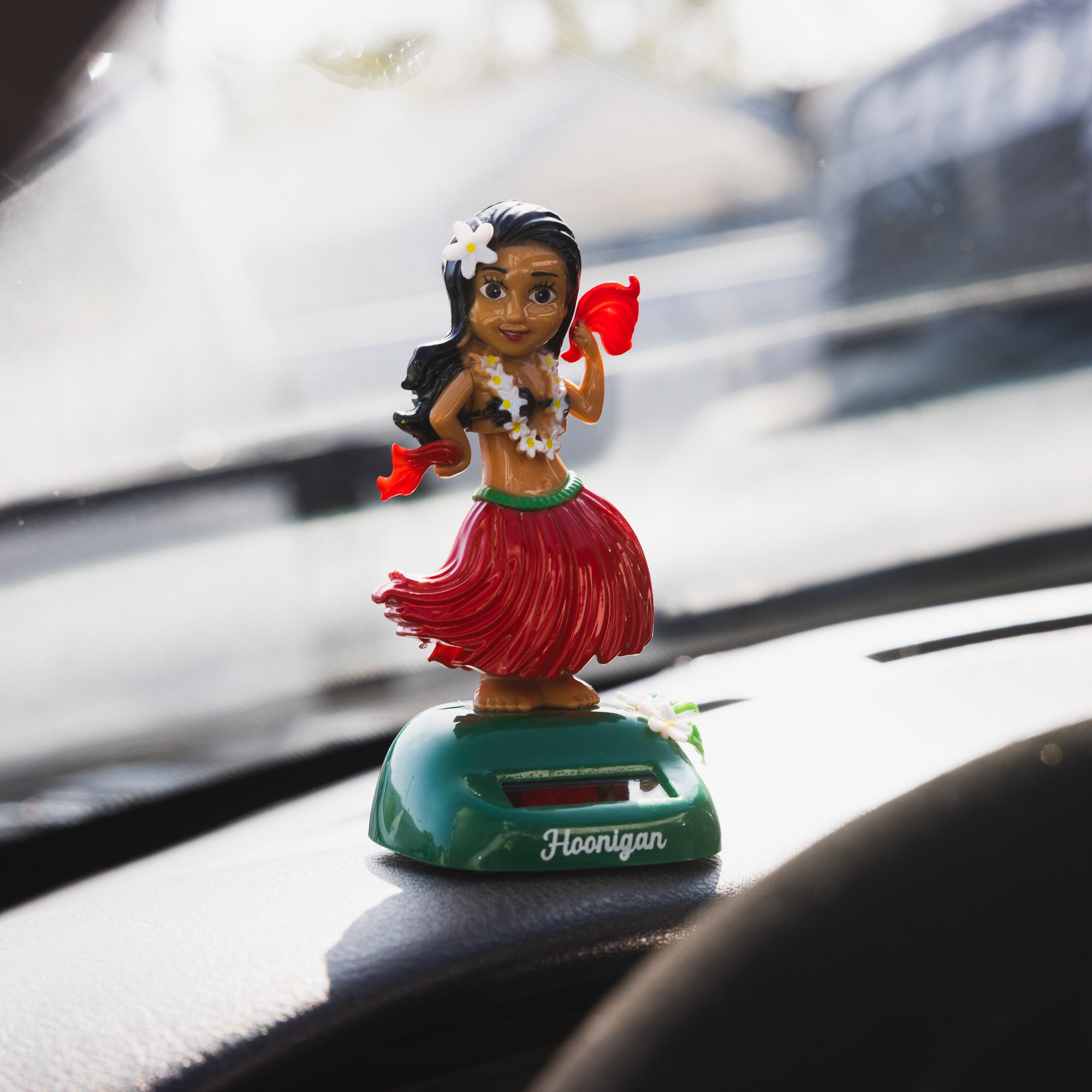 Hoonigan HULAgan GIRL graphic featuring a female character in a vibrant hula outfit, surrounded by tropical elements and bold colors.