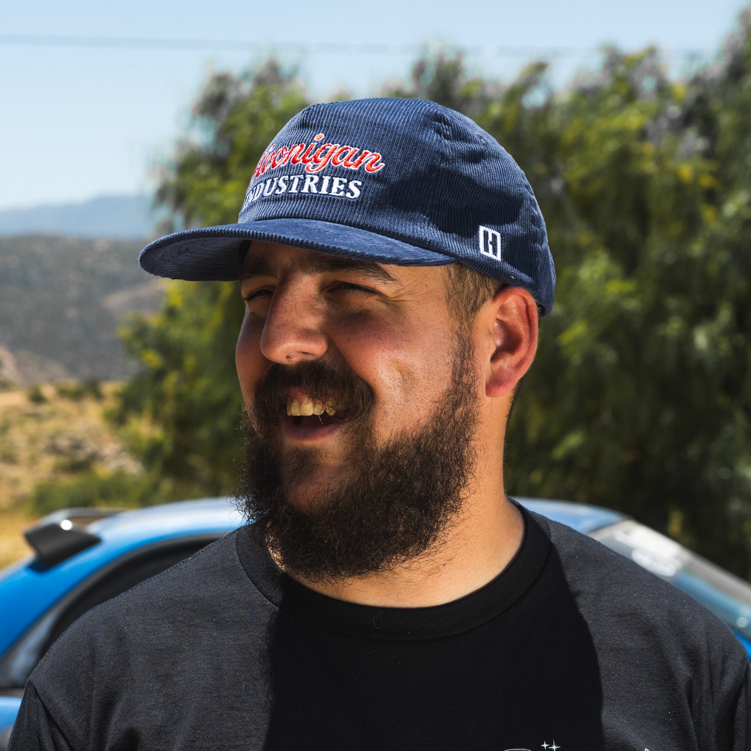 Hoonigan ROCKIES unstructured snapback hat featuring a black fabric, curved brim, and embroidered white logo on the front.