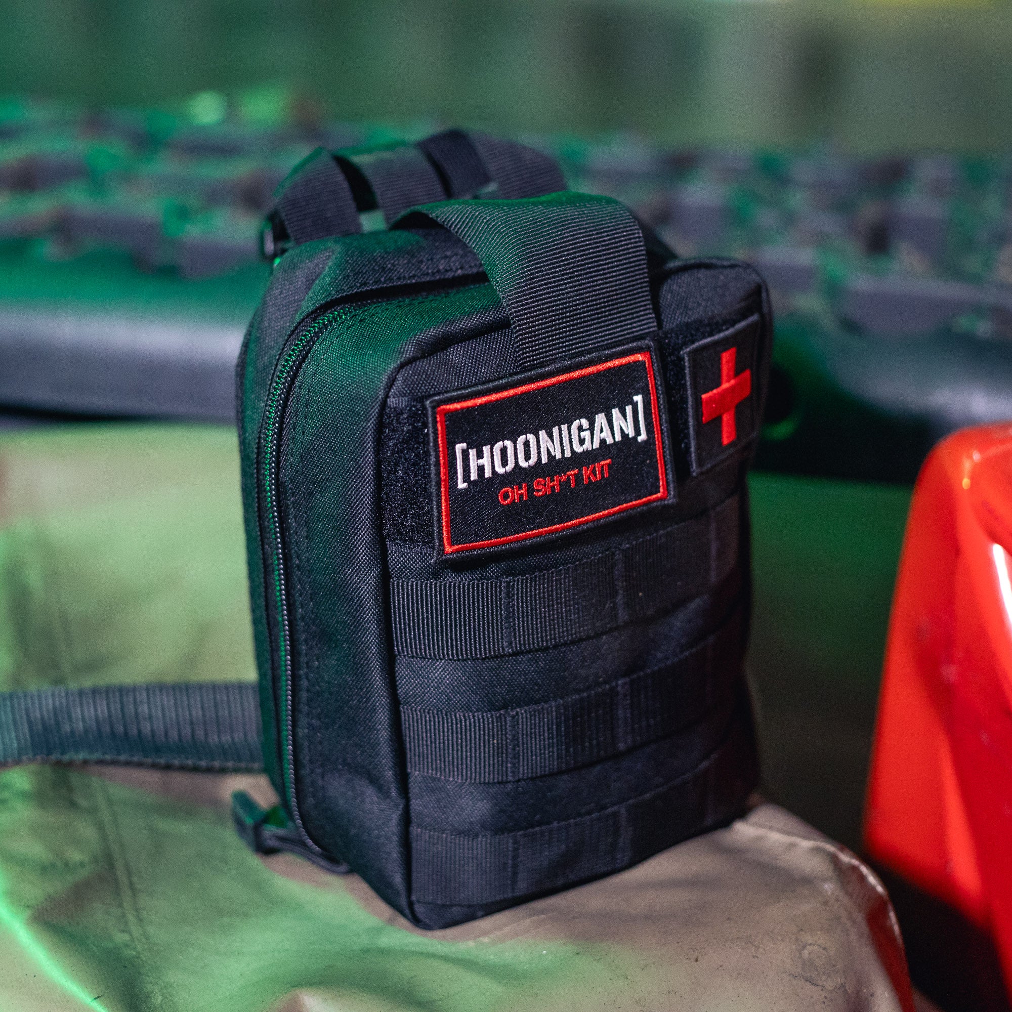 Black Hoonigan OH SH*T Safety Kit pouch with red and white patches, featuring a red cross, on a metallic surface.