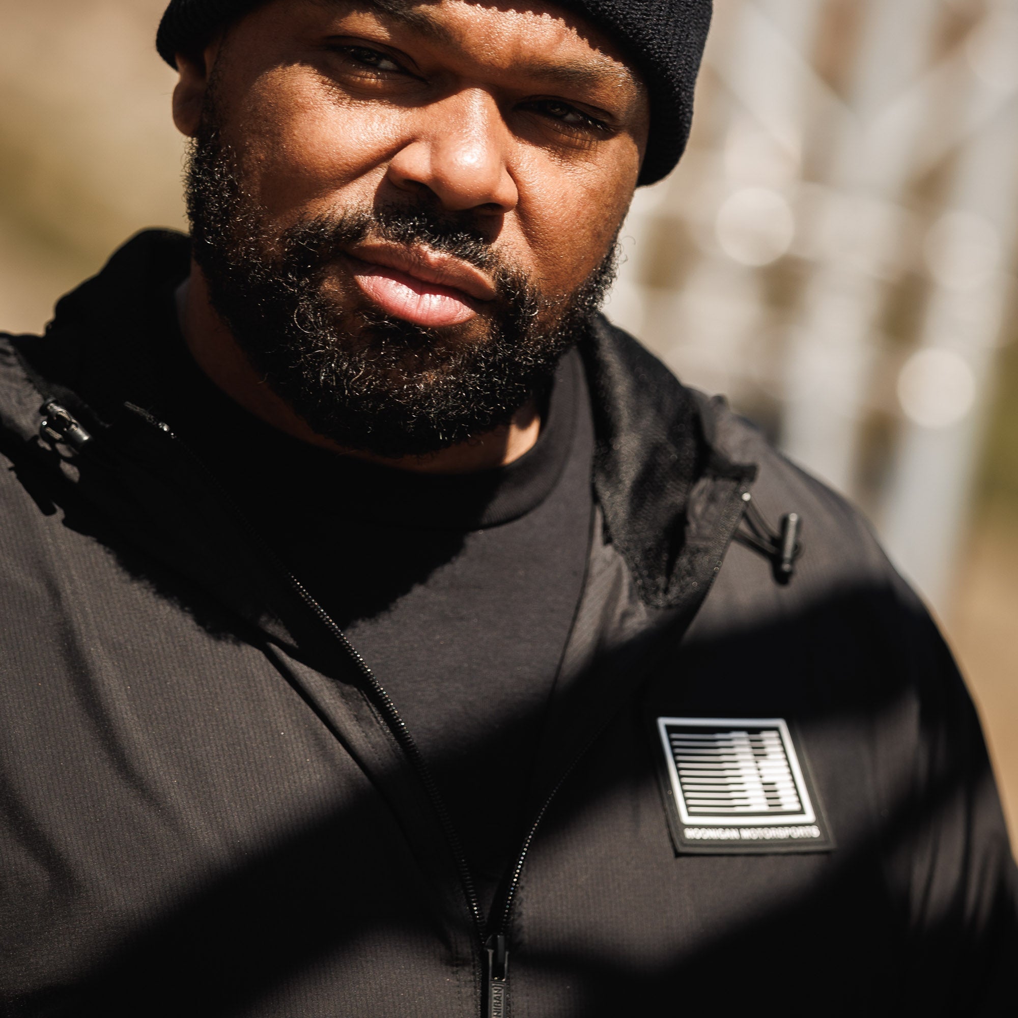 Hoonigan Motorsports windbreaker jacket with a black design featuring logo graphics on the chest and back.