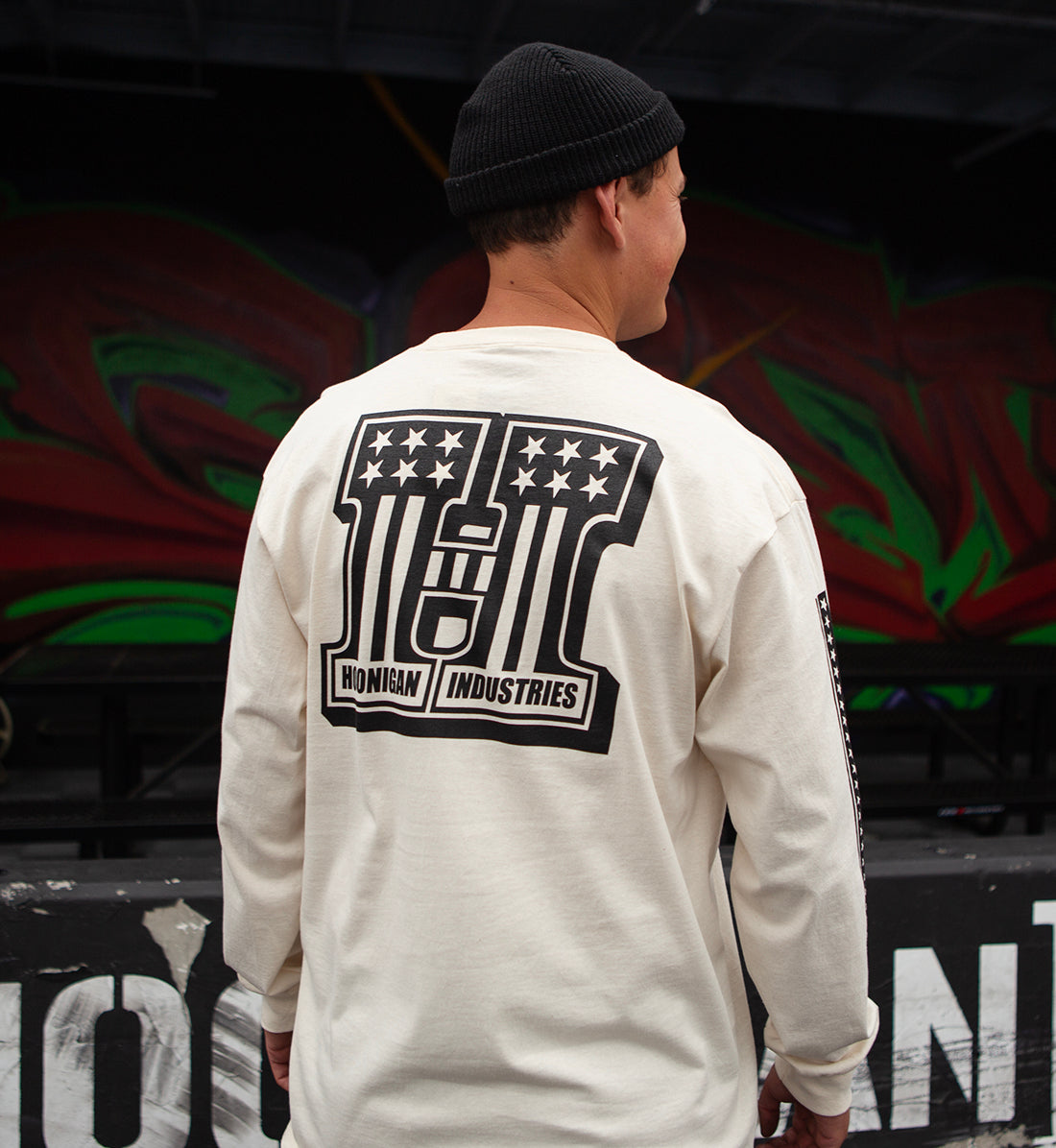 Hoonigan HARDTAIL Long Sleeve Tee displayed in a casual lifestyle setting, featuring a natural color and the brand logo prominently on the chest.