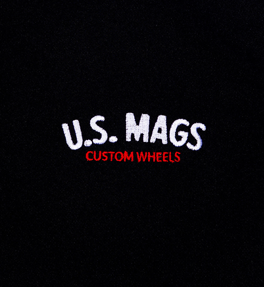 Close-up of black fabric with embroidered text: "U.S. MAGS" in white and "CUSTOM WHEELS" in red.